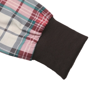 Detail of plaid fabric stitching with dark brown ribbed knit cuffs on women's sweatshirt