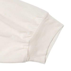 Detailed close-up of white knitted bodysuit sleeve with elastic ribbed cuff design
