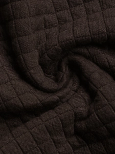 Macro shot of dark brown quilted fabric showing detailed diamond texture and soft material