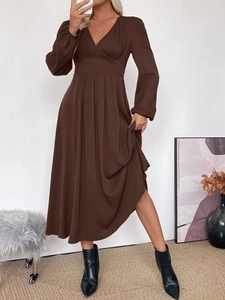 Detail of V-neck long sleeve brown dress featuring high waist and pleated skirt