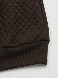 Detail of dark brown quilted sweatshirt fabric with classic diamond pattern and ribbed cuffs