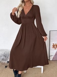 Detail view of deep brown V-neck dress with high waist pleats and lantern cuffs