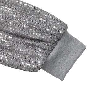 Détail du tissu à paillettes argentées avec poignets en maille côtelée élastique de robe