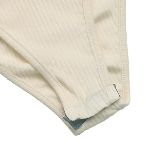 Détail d'un body en maille côtelée beige avec fermeture à boutons-pression au bas