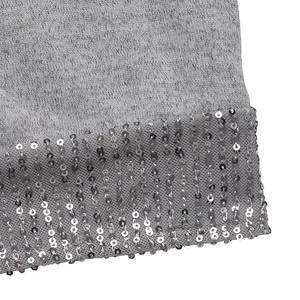 Détail macro d'une robe en maille grise avec des rangées verticales de paillettes argentées