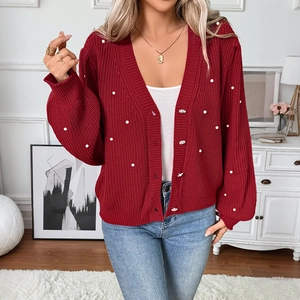 Detailed close-up of red knit cardigan with white pearl bead accents and V-neckline