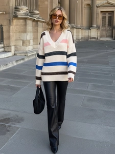 Street style view of a color-block striped V-neck knitted sweater with leather pants