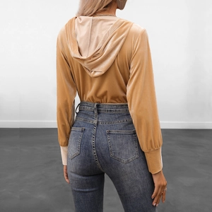 Back view of a woman wearing a yellow velvet hoodie and slim-fit high-waisted denim jeans