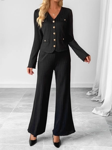 Detailed texture of black knit set with V-neck top and wide-leg pants with gold buttons