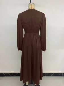 Macro detail of high-waist pleated design and matte fabric on a brown long sleeve dress