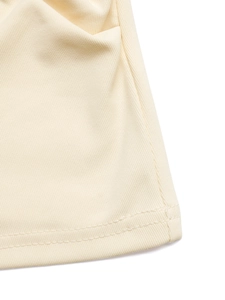 Detailed close-up of beige ribbed knit fabric texture and high-quality hem stitching detail