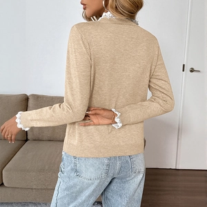 Detail of the elegant white crochet lace trim on the collar of a beige knitted sweater
