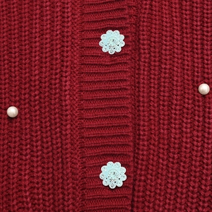 Macro shot of red knit cardigan with rhinestone flower buttons and pearl accents