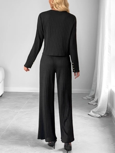 Macro detail of black ribbed knit set showing golden buttons on the sleeve and texture