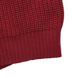 Close-up detail of red chunky knit sweater showing rib-knit hem and thick wool texture