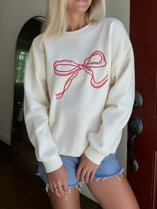 Macro detail of red bow print on cream oversized long sleeve sweatshirt with ribbed cuffs
