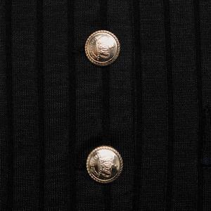 Detail of black ribbed knit fabric with two ornate golden crown crest buttons