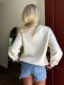 Back view of a cream oversized long sleeve sweatshirt styled with denim shorts
