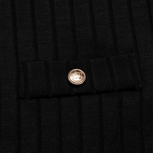Close-up of black ribbed knit fabric with a decorative gold crown relief metal button