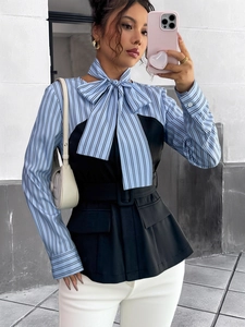Detail of striped shirt with black vest overlay, bow tie neckline, and waist belt