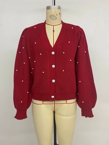 Detail of red V-neck knit cardigan featuring floral buttons and white pearl decorations