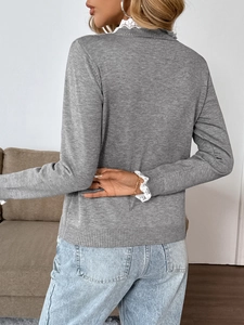 Close-up of white lace trim on grey knit sweater sleeves with an elegant layered look