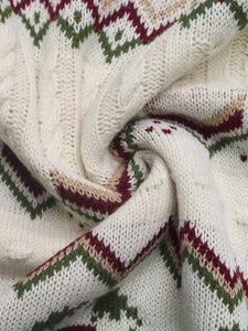 Detail of chunky knit fabric with ethnic geometric patterns in red and green colors