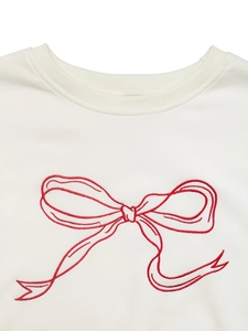Detail shot of the delicate red ribbon embroidery on a white crewneck sweatshirt fabric