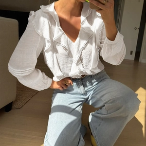 Detailed close-up of delicate white lace edging and ruffle trim on the V-neck blouse