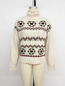 Detail of cable knit pattern and geometric jacquard embroidery on white turtleneck sweater