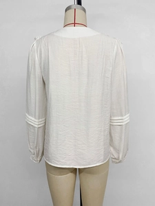 Rear view of white long-sleeved shirt featuring textured fabric and ruffled sleeve details
