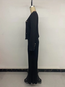 Detail of black textured knit set showing golden buttons and vertical rib pattern