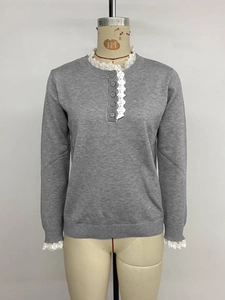 Close-up of grey knit sweater showing white lace trim on collar and decorative buttons