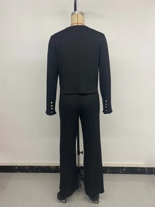 Detail of black knit set featuring vertical ribbed texture and gold sleeve buttons