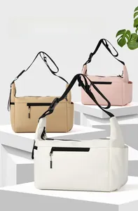 Tre borse a tracolla in nylon in beige, rosa e bianco su supporti geometrici in dettaglio