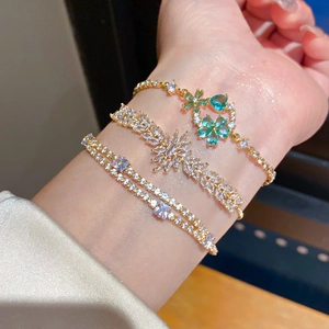 Detailed close-up of 18k gold-plated flower charm and zircon leaf bracelet set on a wrist