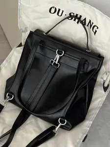 Detail view of the silver metal lock and waxed leather texture on the black backpack