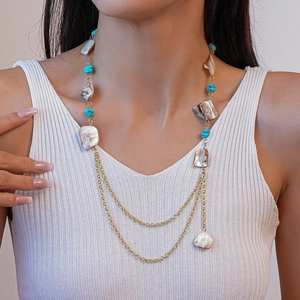 Detail of bohemian shell and turquoise beaded necklace with layered gold chains