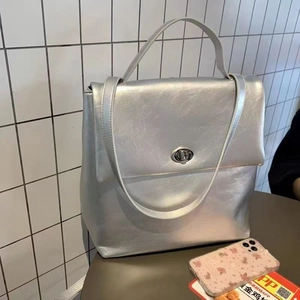 Detailed view of silver metallic leather backpack featuring a secure metal twist lock closure