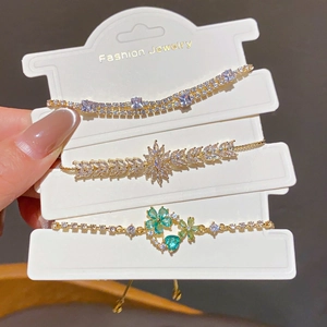 Detailed view of three 18k gold plated bracelets with zircon flower and droplet charms
