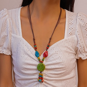 Detail of Bohemian beaded necklace with green round pendant on model wearing lace