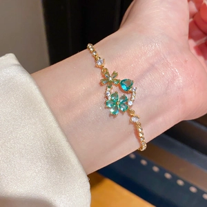 Detailed shot of 18k gold flower bracelet with turquoise gemstones on female wrist