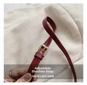 Close-up of red leather bucket bag strap with adjustable gold buckle and fine stitching