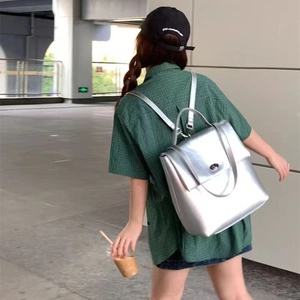 Silver faux leather backpack with metallic finish shown on model in urban setting