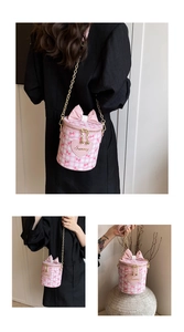 Detailed view of pink plaid bucket bag featuring cherry prints and a golden chain strap