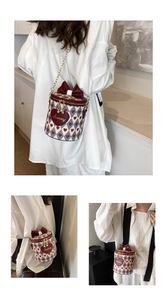 Detail of heart pattern bucket bag with bow decoration and gold chain strap