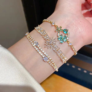 Close-up of 18k gold plated flower and heart bracelets layered on a female wrist
