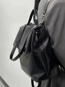 Minimalist black shiny faux leather backpack for women with flap closure and adjustable straps