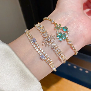 Detailed view of layered 18k gold plated bracelets with floral and teardrop crystals