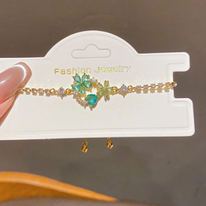 Detail of 18k gold plated bracelet featuring green and blue crystal flowers and hearts